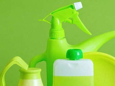 Monochrome green bottles and containers for liquids or gel with plastic bottle and lids on green background